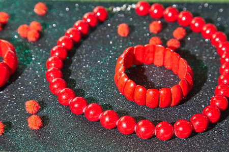 Red beads lying on an unusual surface and red braceletの写真素材