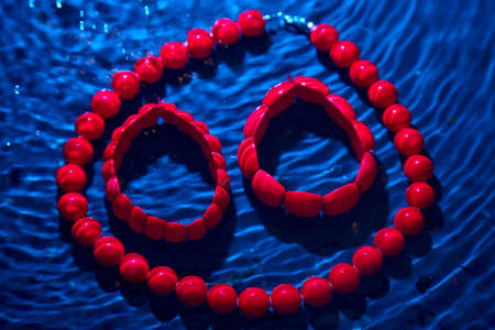 Red beads lying on an unusual surface and red braceletの写真素材
