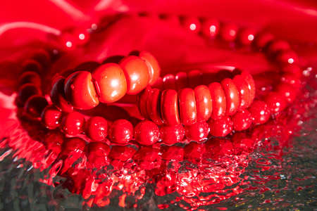 Red beads lying on an unusual surface and red braceletの写真素材