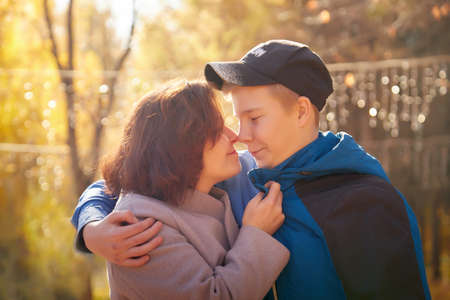 Mother and adult son in autumn park or forest in sunny day. Happy family walking outdoorsの写真素材