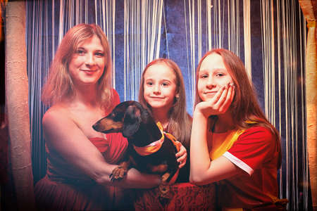Family during a stylized theatrical circus photo shoot in a beautiful red location. Models mother...