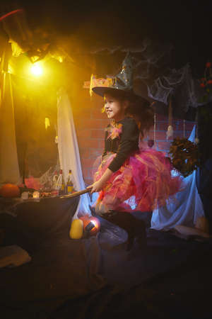Cute little girl in costume for witch in the room decorated fot Halloweenの写真素材