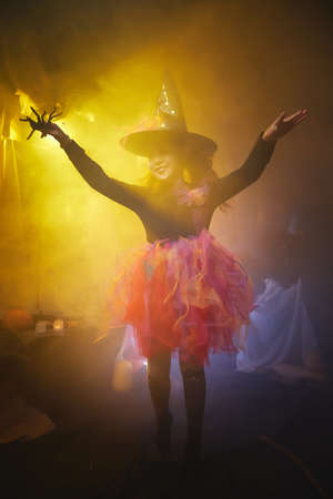 Cute little girl in costume for witch in room decorated fot Halloweenの写真素材