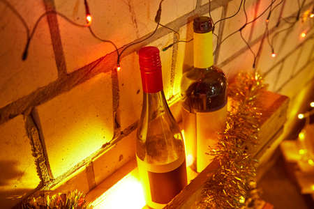 Christmas lights near bottles on background with bricks
