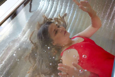 Beautiful girl with long hair underwater in the swimming pool. Young woman and diving