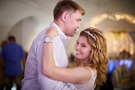 Kirov, Russia - July 18, 2020: Bridge and groom dancing together indoors and people guests backgroundのeditorial素材