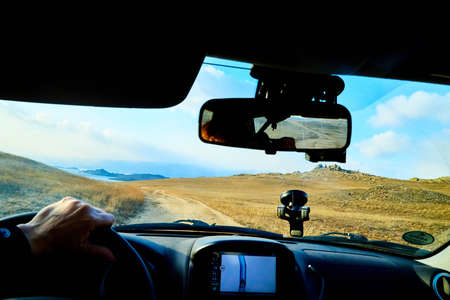 Siberia Baikal, Russia - November 20, 2020: View from of car interior from side of driver to the road and autumn yellow nature landscape with hills through the windshieldのeditorial素材