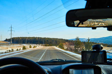 Siberia, Russia - November 28, 2020: View from of car interior from side of driver to the road and nature landscape through windshieldのeditorial素材