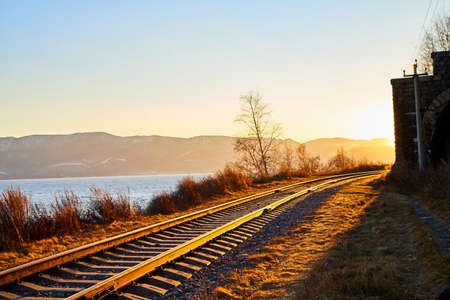 Circum Baikal railway running along the shore of Lake Baikal on an autumn sunny day with yellow landscape aroundの写真素材