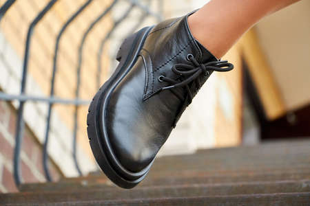 Black female or male leather shoes on legs of woman. Shooting for catalog or an online store...