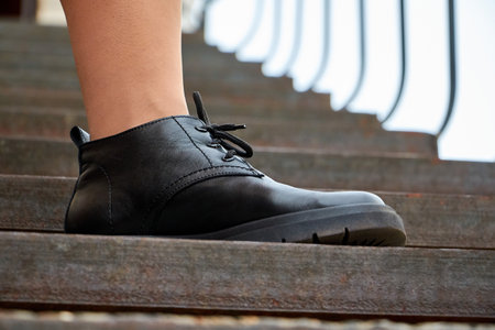 Black female or male leather shoes on legs of woman. Shooting for catalog or an online store outside. A pair of shoes on a girl on the streetの写真素材