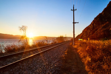 Circum Baikal railway running along the shore of Lake Baikal on an autumn sunny day with yellow...