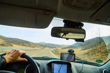 Siberia Baikal, Russia - November 20, 2020: View from of car interior from side of driver to the road and autumn yellow nature landscape with hills through windshieldのeditorial素材