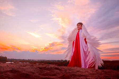 Beautiful young woman or girl with curly hair and in red dress with a light flying fabric and white...