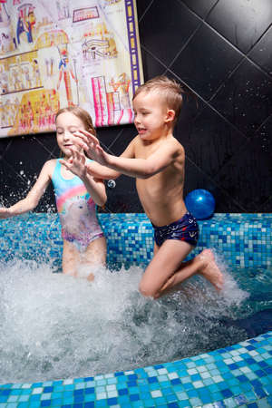 Kirov, Russia - March 22, 2021: Nice children swiming in blue small pool. Girl and boy have fun in nice water indoorsのeditorial素材