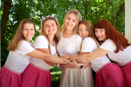 Kirov, Russia - July 29, 2021: Bride with bridesmaids in the same short pink skirts in green park in summerのeditorial素材