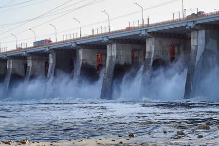 Dam of a reservoir with falling water and a wave on a summer or spring day. Nature landscape with...