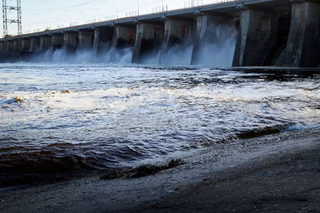 Dam of a reservoir with falling water and a wave on a summer or spring day. Nature landscape with...