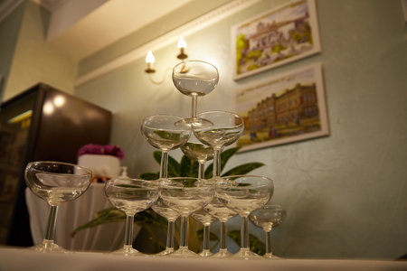 Kriov, Russia - July 03, 2021: Glasses in the restaurant stand like a pyramid waiting for champagne or wine. Paintings on the wall in the restaurantのeditorial素材