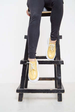 Beautiful yellow sneakers and woman legs in the studio on white background. Fashionable shooting of young girl with beautiful legsの写真素材