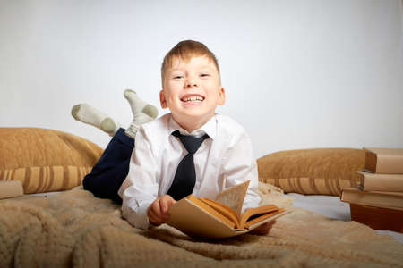 Schoolboy in uniform with big book in the living room. A boy during a photo shoot about school. September 1 holiday in Russiaの写真素材