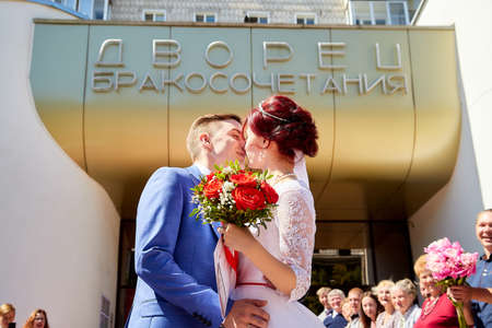 Kirov, RUSSIA - June 20, 2020: The newlyweds near the registry office and people, guests, relatives rejoice and throw rose petals. The tradition of meeting bride and groom in Russiaのeditorial素材