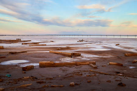 The shore of salt lake with puddles of water and sand, an endless horizon, a blue sky with white...