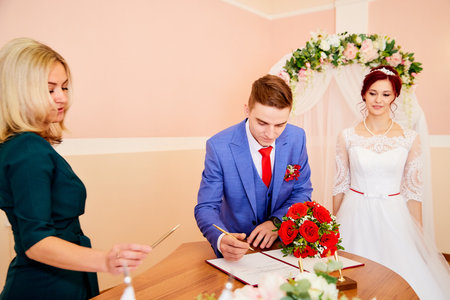 Kirov, Russia - June 20, 2020: The bride and groom sign the official document during the marriage ceremony at the registry office in Russia in the presence of manager. The concept of love and familyのeditorial素材