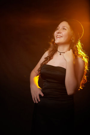 Portrait of an elegant nice fun happy teenager girl in a black hat and dress. Studio shot. Posing...