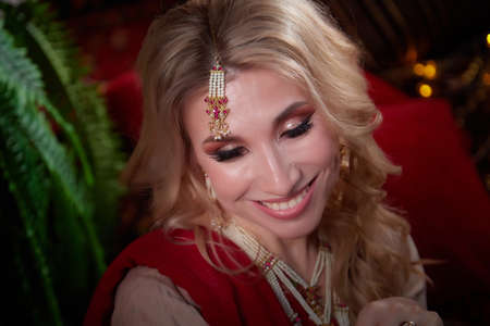 A beautiful European girl looking like an Arab woman in a red room in a harem. Photo shoot of an...
