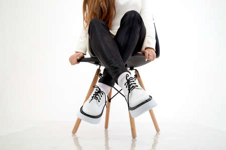 Beautiful white sneakers and woman legs in the studio on white background. Fashionable shooting of young girl with beautiful legsの写真素材