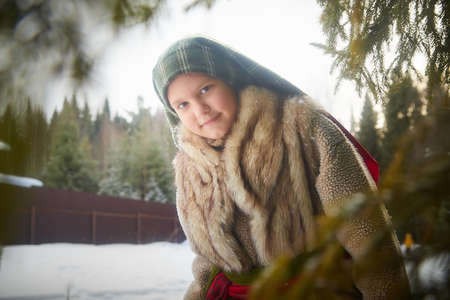 Portrait of a nice cute teenager girl in old peasant clothes with hot fur coat and shawl in cold...