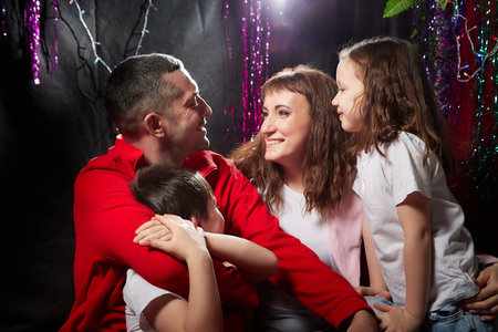 Lovely Family with mother, father, son and daughter having fun in room derorated fot Christmas...