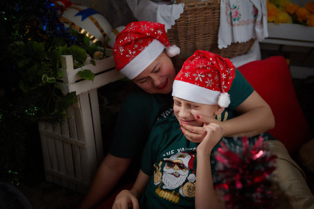 Kirov, Russia - January 03, 2022: Beautiful mother and her son in cozy room decorated for Christmas. The concept of a friendly family on holidayのeditorial素材