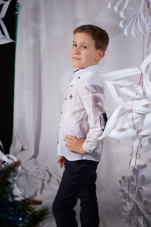 Kirov, Russia - January 15, 2022: Portrait of a handsome boy in a white clothes in the room decorated for Christmas with snowflake. Winter Kid's fashionのeditorial素材