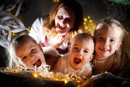 Christmas portrait of big family with mother and three sisters in home holiday living room decorated for holiday with light of garlandの写真素材