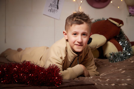 Kirov, Russia - January 03, 2022: Portrait of a handsome disabled boy with autism and cerebral palsy in warm sweater in the room decorated for Christmas with nice lights. Kid's winter fashionのeditorial素材