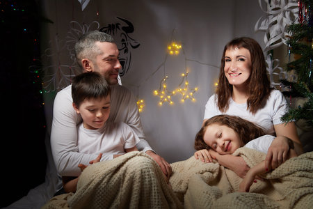 Lovely Family with mother, father, son and daughter having fun in the room derorated fot Christmas...