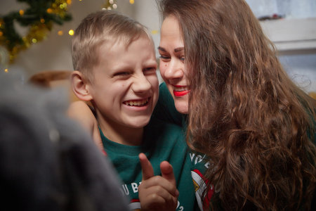 Kirov, Russia - January 03, 2022: Beautiful mother and her disabled son with autism and cerebral palsy in cozy room decorated for Christmas. The concept of friendly family on a holidayのeditorial素材