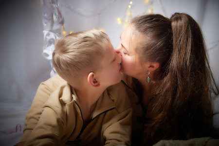 Kirov, Russia - January 03, 2022: Beautiful mother and her disabled son with autism and cerebral palsy in cozy room decorated for Christmas. The concept of friendly family on a holidayのeditorial素材