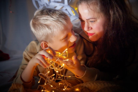 Kirov, Russia - January 03, 2022: Beautiful mother and her disabled son with autism and cerebral palsy in cozy room decorated for Christmas. The concept of friendly family on a holidayのeditorial素材