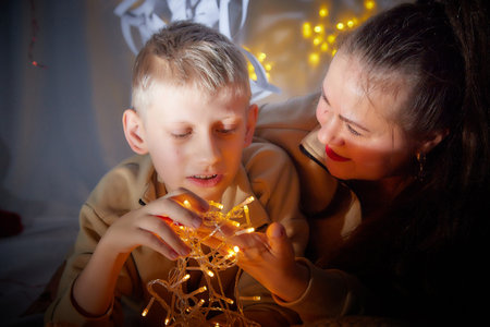Kirov, Russia - January 03, 2022: Beautiful mother and her disabled son with autism and cerebral palsy in cozy room decorated for Christmas. The concept of friendly family on a holidayのeditorial素材