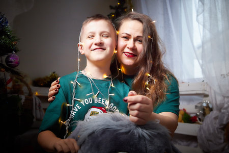 Kirov, Russia - January 15, 2022: Beautiful mother and her son in cozy room decorated for Christmas. The concept of a friendly family on holidayのeditorial素材