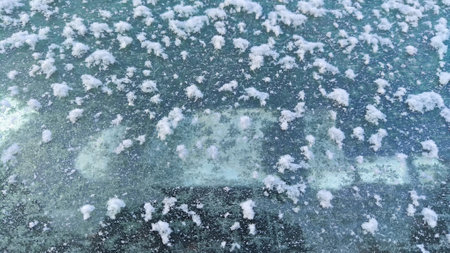 Abstract winter background and texture with white snow on the glass. Beauty nature transparent crystal frosty ice with blurred outside on window at cold day after snow, selective focusの写真素材