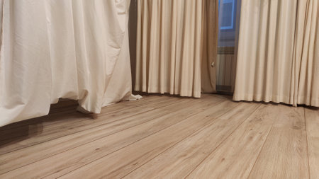 Floor has laminate boards with a wooden texture and curtains for the background in pastel colors. Abstract laminate flooring and fabric curtains, tilt shooting, partial focusの写真素材