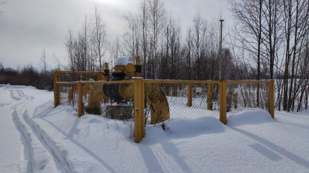 Gas valves with snow in winter frost. Gas line valves behind metal fenceの写真素材