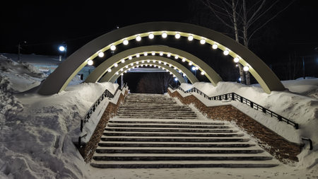 Arch with white lanterns on city street on a dark winter night and white snow drifts. Background photo shootの写真素材