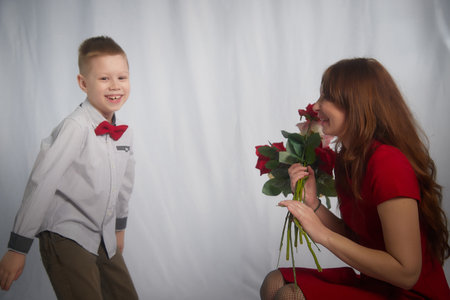 Woman with a boy with flower. Mom with son on a white background in mothers Day. Family portrait with mother and boy having fun togetherの写真素材