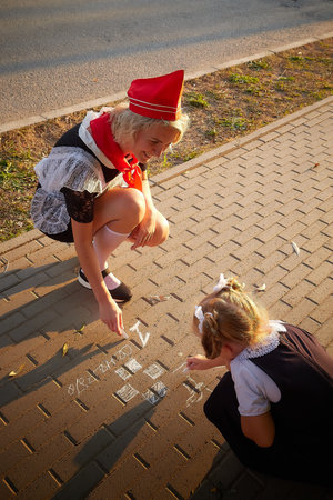 Young and adult schoolgirl on September 1 drawing by chalk on asphalt. Generation of schoolchildren of USSR and Russia. Female pioneer in red tie and October girl in modern uniform. Mom and daughterの写真素材