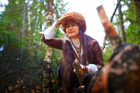Girl in a leather jacket, a big red fox fur hat in the forest in autumn. A female model poses as a...